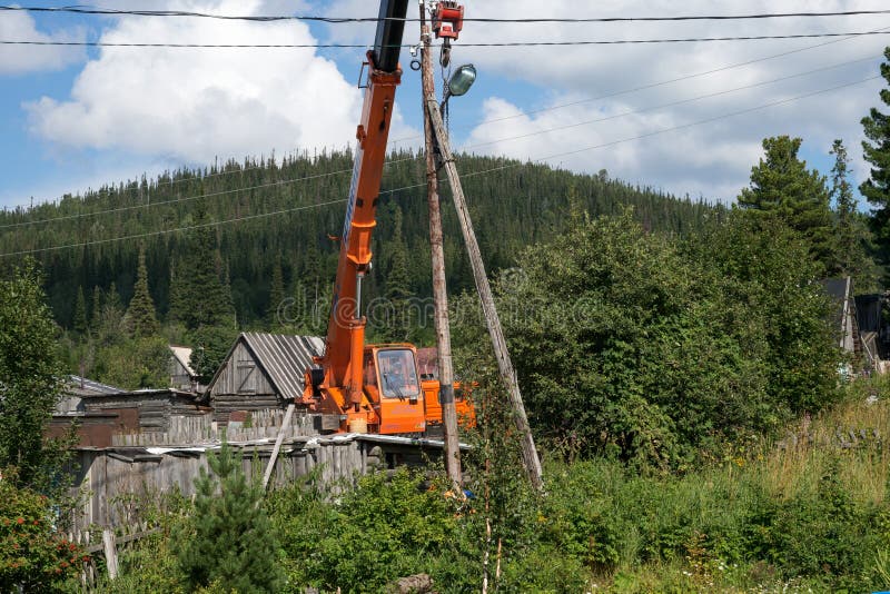 Erigendo la gru pronta a smantellare la vecchia trasmissione di legno elevi sulle periferie del villaggio immagine stock Erigendo la gru pronta a smantellare la vecchia trasmissione di legno elevi sulle periferie del villaggio immagine stock