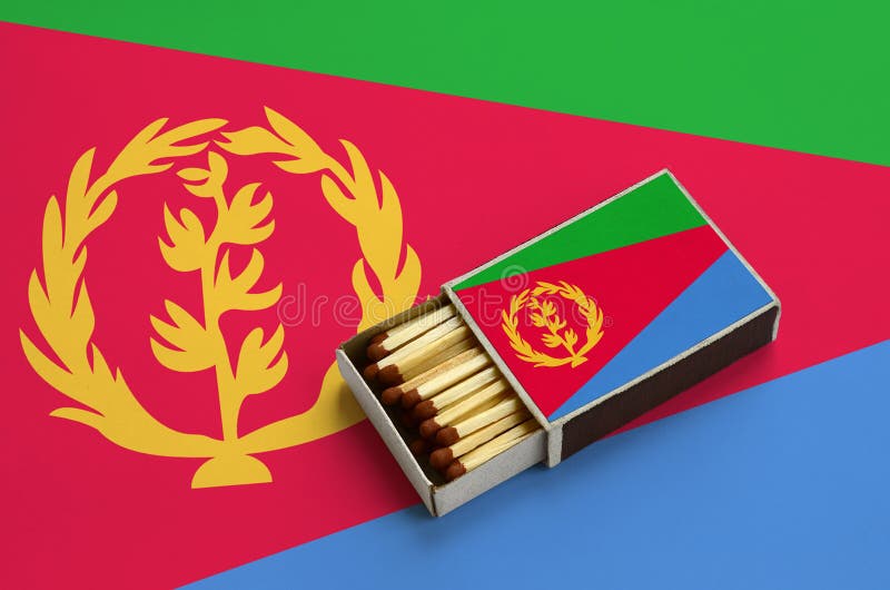 Eritrea flag is shown in an open matchbox, which is filled with matches and lies on a large flag royalty free stock photos