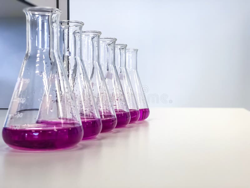 The Erlenmeyer Flask on bench laboratory, with bright pink solvent solution from titration experiment, acidity, alkalinity in wastewater sample. Has copy space use as a science background. The Erlenmeyer Flask on bench laboratory, with bright pink solvent solution from titration experiment, acidity, alkalinity in wastewater sample. Has copy space use as a science background.