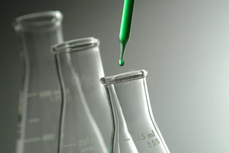 Laboratory pipette with drop of green liquid over glass conical Erlenmeyer flasks for an experiment in a science research lab. Laboratory pipette with drop of green liquid over glass conical Erlenmeyer flasks for an experiment in a science research lab
