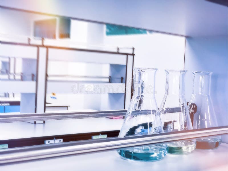 Erlenmeyerkolvar på hyllor i kemiskt laboratorium med blå lösningsmedelsindikator, titreringsvattenprov arkivbild Erlenmeyerkolvar på hyllor i kemiskt laboratorium med blå lösningsmedelsindikator, titreringsvattenprov arkivbild