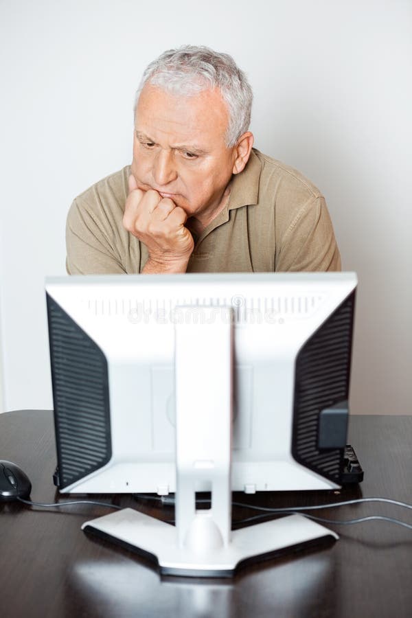 Ernster älterer Mann, der Computer-Monitor in der Klasse betrachtet stockfotografie Ernster älterer Mann, der Computer-Monitor in der Klasse betrachtet stockfotografie