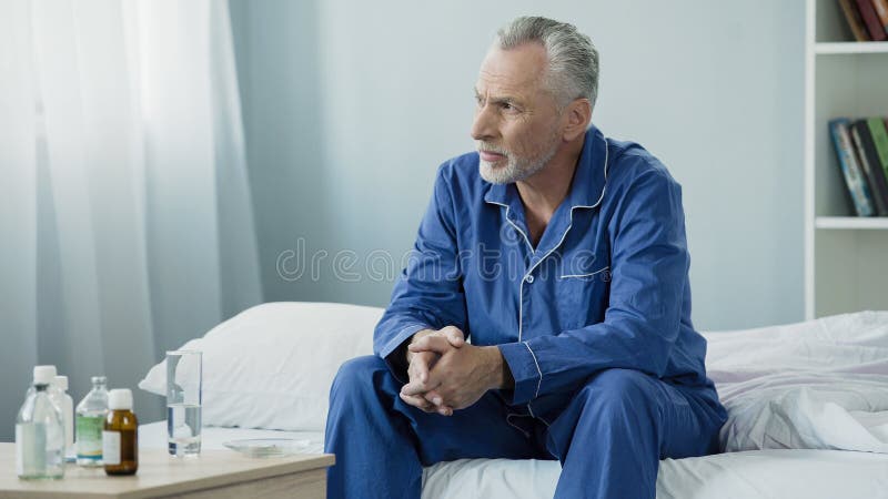 Ernstes gealtertes Mannsitzen zu Hause gestört und nachdenklich auf Bett, einsame kranke Person stockfotos Ernstes gealtertes Mannsitzen zu Hause gestört und nachdenklich auf Bett, einsame kranke Person stockfotos