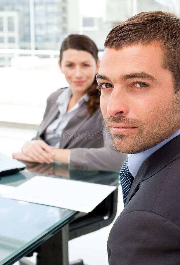 Serious businesspeople sitting around a table and looking at the camera. Serious businesspeople sitting around a table and looking at the camera