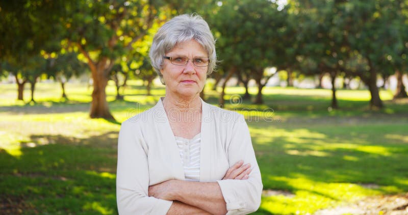 Ernstige hogere vrouw die zich in het park bevinden stock afbeeldingen Ernstige hogere vrouw die zich in het park bevinden stock afbeeldingen