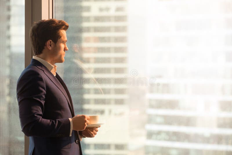 Ernstige peinzende zakenman het drinken koffie, die zonsopgang bekijken royalty-vrije stock fotografie Ernstige peinzende zakenman het drinken koffie, die zonsopgang bekijken royalty-vrije stock fotografie