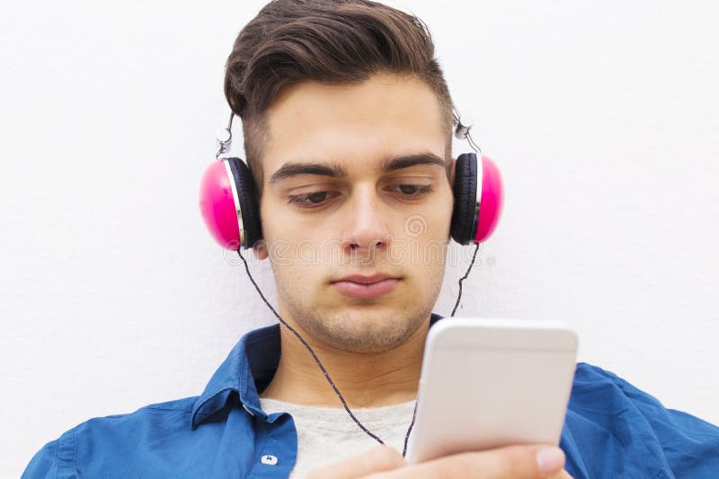 Ernstige tienerjongen met hoofdtelefoons en mobiele telefoon royalty-vrije stock afbeeldingen Ernstige tienerjongen met hoofdtelefoons en mobiele telefoon royalty-vrije stock afbeeldingen