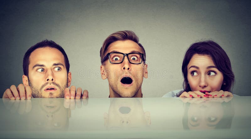 Erschrockene Leute zwei Männer und eine Frau, die Form unter die Tabelle spähend sich versteckt stockfoto Erschrockene Leute zwei Männer und eine Frau, die Form unter die Tabelle spähend sich versteckt stockfoto