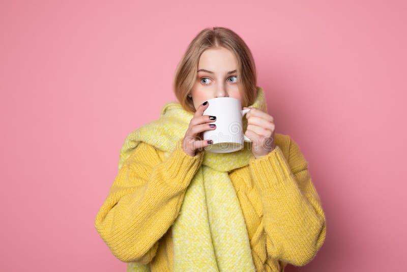 Erschrockenes blondes M?dchen in der gelben Strickjacke und im Schal, trinkender hei?er Tee stockbilder Erschrockenes blondes M?dchen in der gelben Strickjacke und im Schal, trinkender hei?er Tee stockbilder