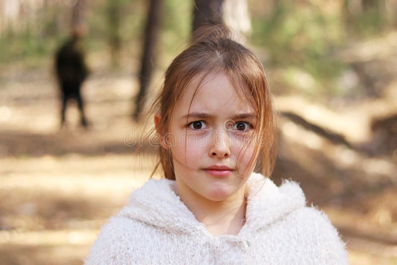 Erschrockenes Mädchen allein im Wald, Mann auf Hintergrund stockbild