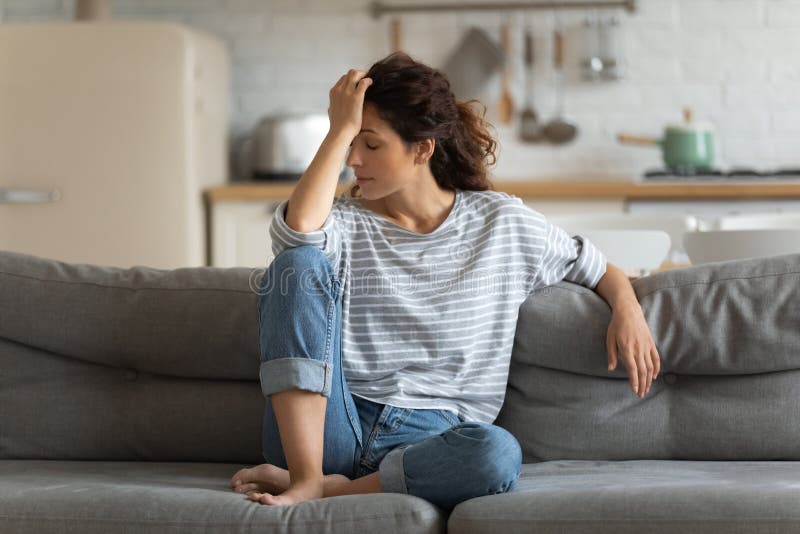 Erschöpfte frustrierte junge Frau, welche die Stirn, saß auf der Couch allein lässt lizenzfreie stockfotos