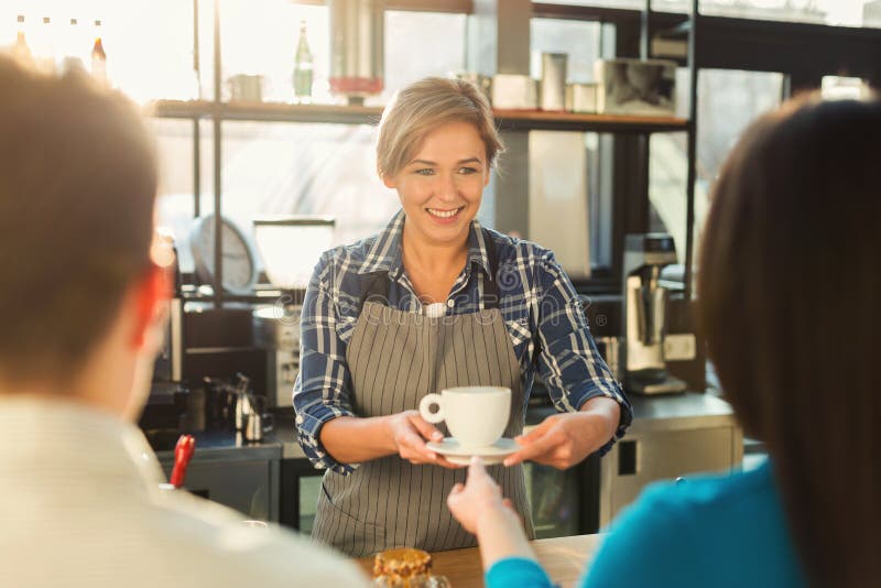Ervaren het glimlachen barista die tot koffie maken aan klanten stock foto Ervaren het glimlachen barista die tot koffie maken aan klanten stock foto
