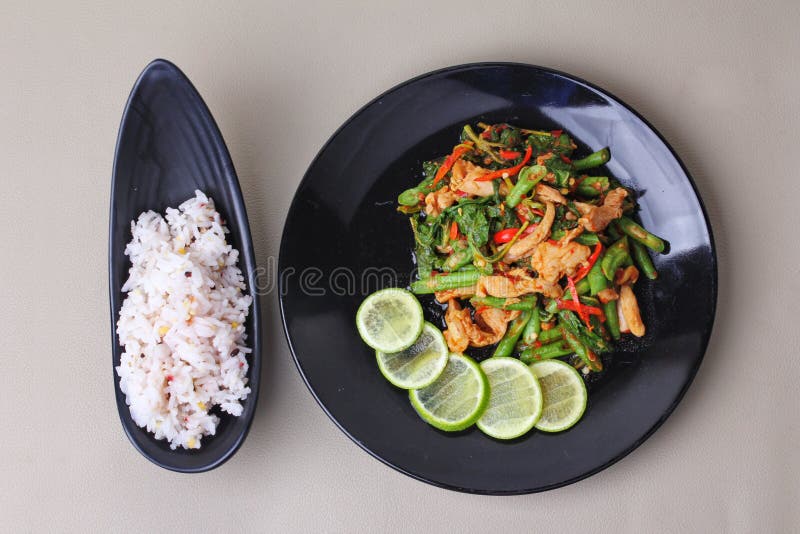 A ervilha fritada picante e a manjericão com carne de porco cobriram o limão verde cortado serviram com a semente japonesa para o fotos de stock A ervilha fritada picante e a manjericão com carne de porco cobriram o limão verde cortado serviram com a semente japonesa para o fotos de stock