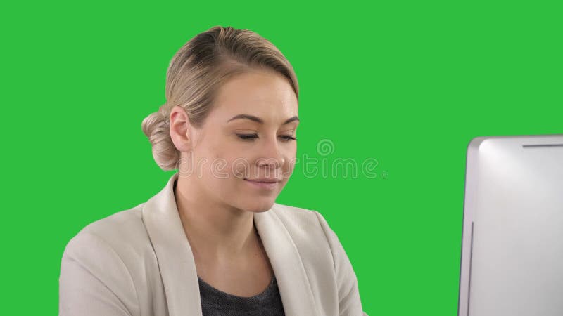 Erwachsene Geschäftsfrau, die Computer im Büro auf einem grünen Schirm, Farbenreinheitsschlüssel betrachtet