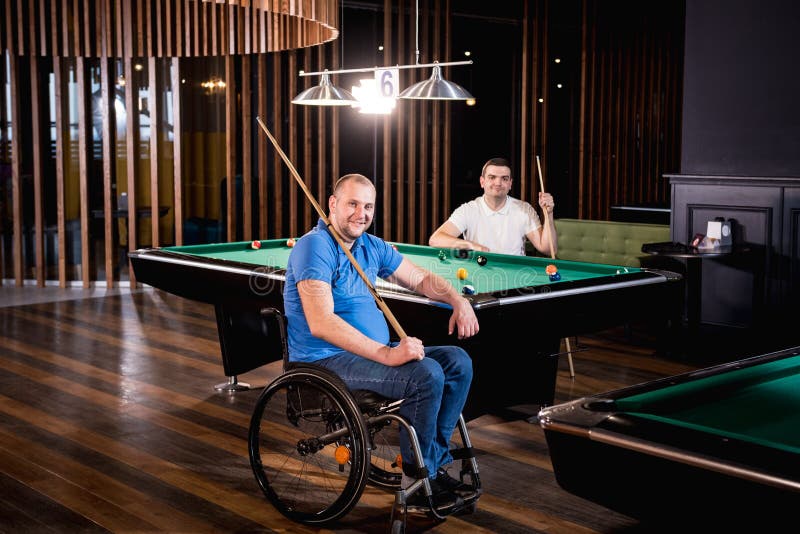 Erwachsene Männer mit Behinderung im Rollstuhl spielen Billard im Club lizenzfreie stockfotografie