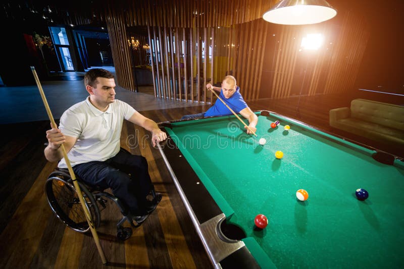 Erwachsene Männer mit Behinderung im Rollstuhl spielen Billard im Club lizenzfreie stockbilder
