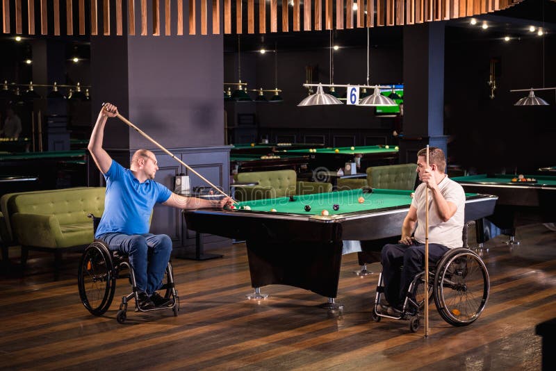 Erwachsene Männer mit Behinderung im Rollstuhl spielen Billard im Club lizenzfreie stockbilder