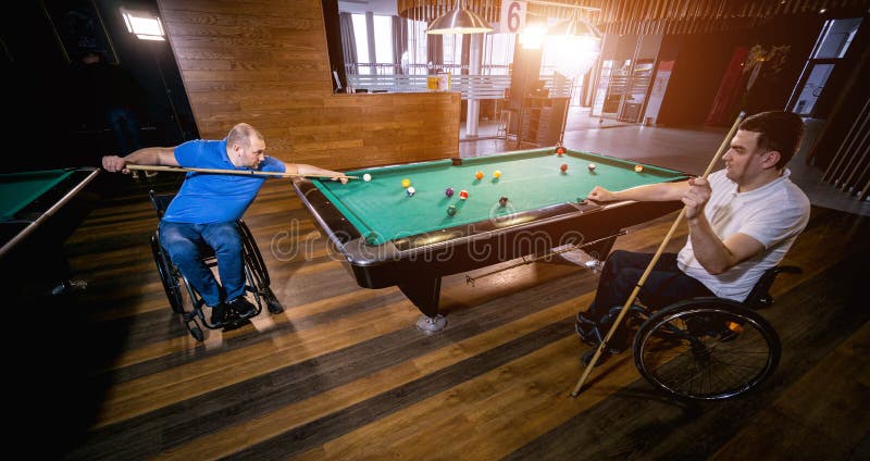 Erwachsene Männer mit Behinderung im Rollstuhl spielen Billard im Club lizenzfreie stockfotografie