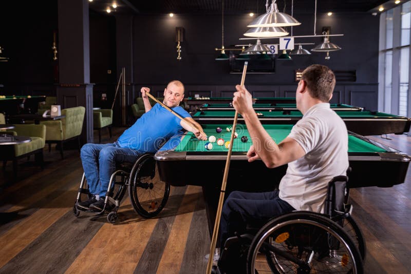 Erwachsene Männer mit Behinderung im Rollstuhl spielen Billard im Club stockfoto