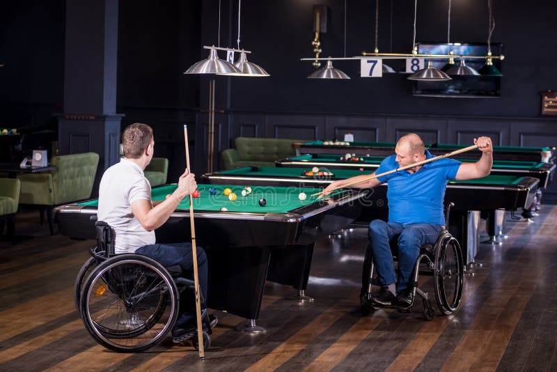 Erwachsene Männer mit Behinderung im Rollstuhl spielen Billard im Club lizenzfreies stockfoto