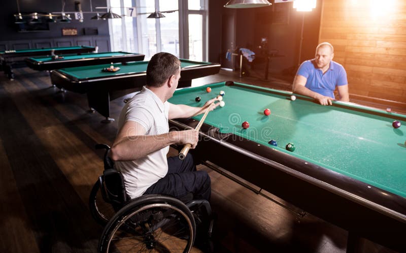 Erwachsene Männer mit Behinderung im Rollstuhl spielen Billard im Club lizenzfreie stockfotos
