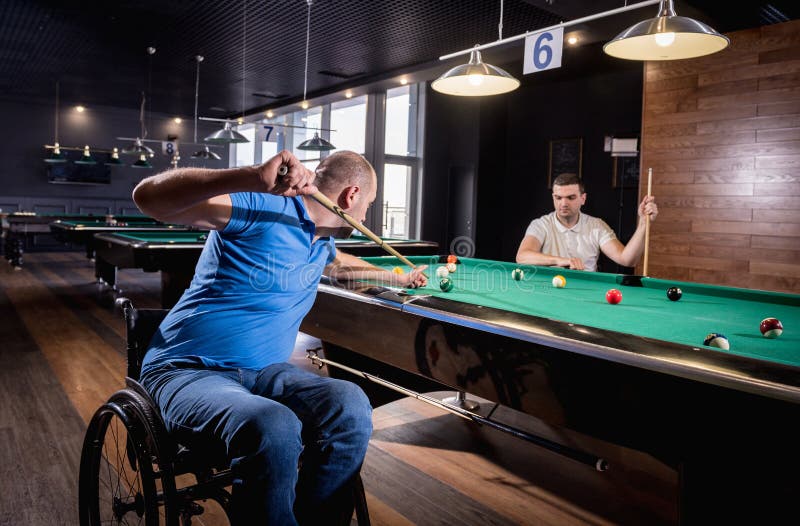 Erwachsene Männer mit Behinderung im Rollstuhl spielen Billard im Club lizenzfreie stockbilder