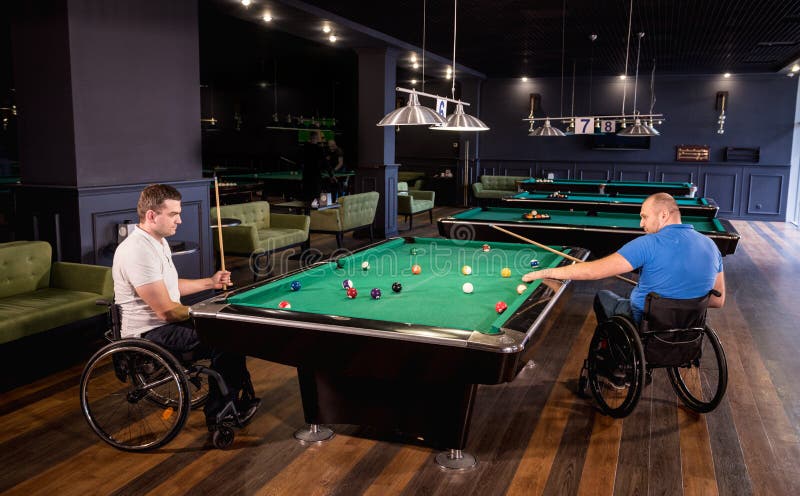 Erwachsene Männer mit Behinderung im Rollstuhl spielen Billard im Club lizenzfreie stockfotografie