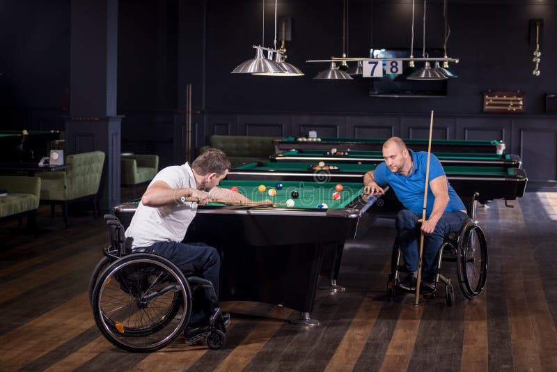 Erwachsene Männer mit Behinderung im Rollstuhl spielen Billard im Club lizenzfreie stockbilder