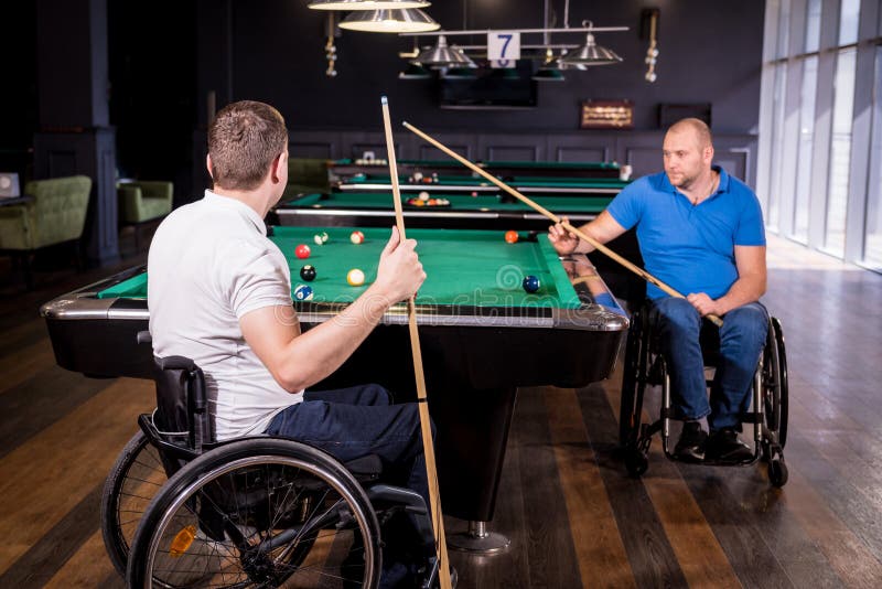 Erwachsene Männer mit Behinderung im Rollstuhl spielen Billard im Club lizenzfreies stockfoto