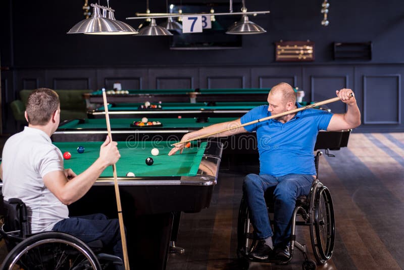 Erwachsene Männer mit Behinderung im Rollstuhl spielen Billard im Club stockfotos
