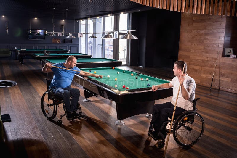 Erwachsene Männer mit Behinderung im Rollstuhl spielen Billard im Club stockbilder