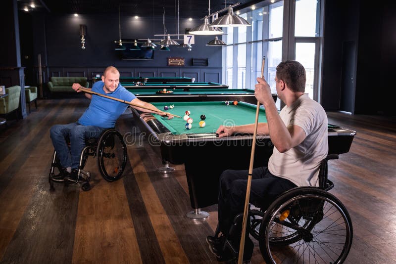 Erwachsene Männer mit Behinderung im Rollstuhl spielen Billard im Club stockfoto