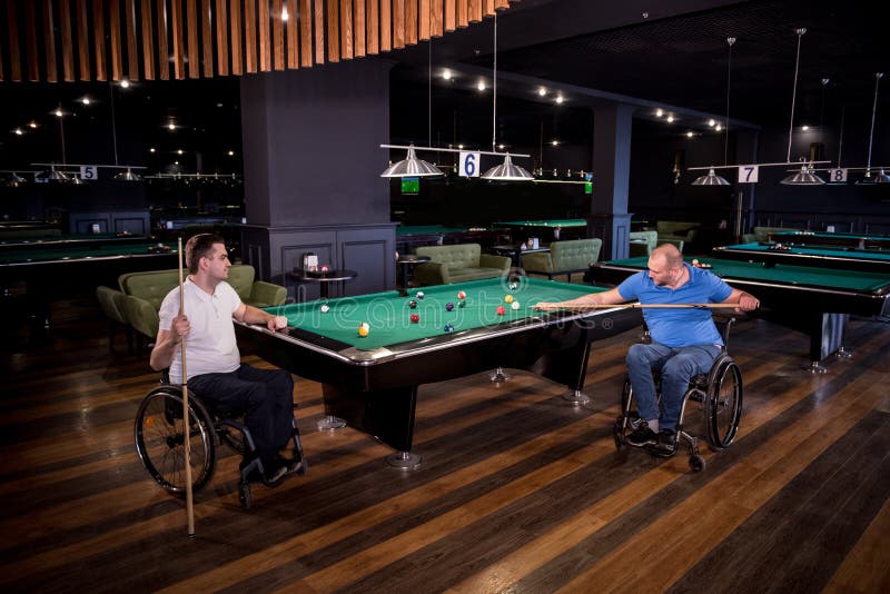 Erwachsene Männer mit Behinderung im Rollstuhl spielen Billard im Club lizenzfreie stockfotografie