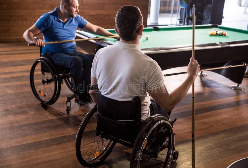 Erwachsene Männer mit Behinderung im Rollstuhl spielen Billard im Club lizenzfreies stockfoto