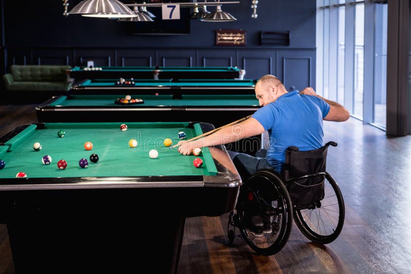 Erwachsene Männer mit Behinderung im Rollstuhl spielen Billard im Club stockfotografie