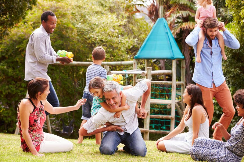 Erwachsene und Kinder, die den Spaß spielt in einem Garten haben