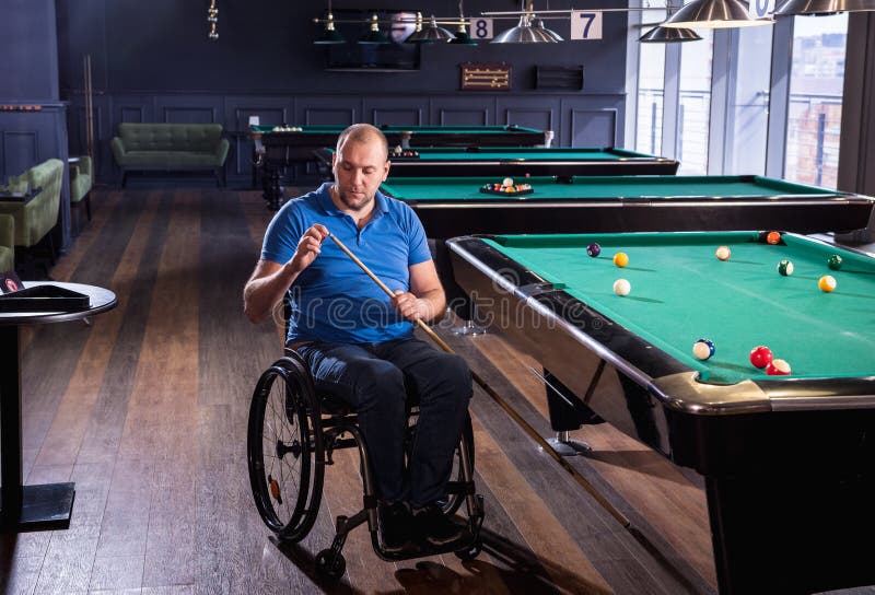 Erwachsener Mann mit Behinderung im Rollstuhl spielen Billard im Club lizenzfreies stockfoto