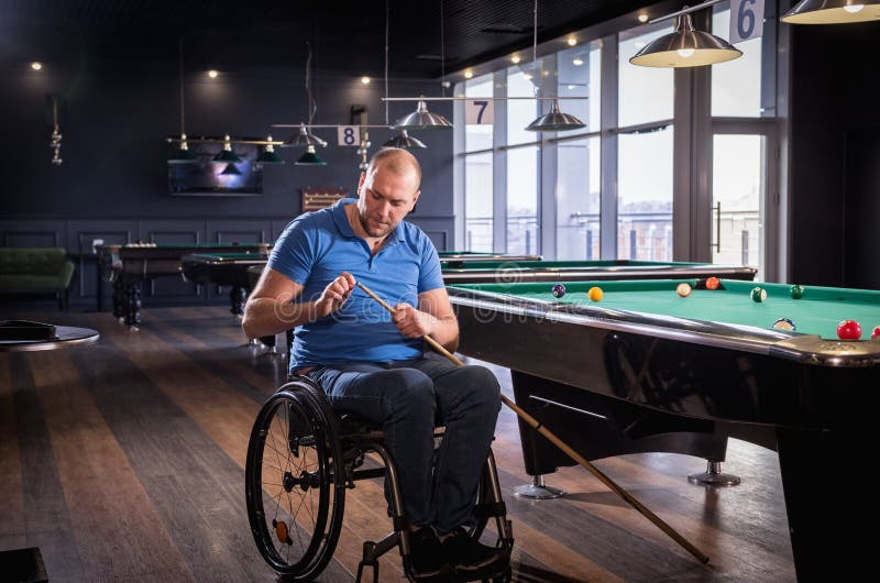 Erwachsener Mann mit Behinderung im Rollstuhl spielen Billard im Club lizenzfreies stockfoto