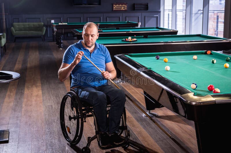 Erwachsener Mann mit Behinderung im Rollstuhl spielen Billard im Club lizenzfreies stockfoto