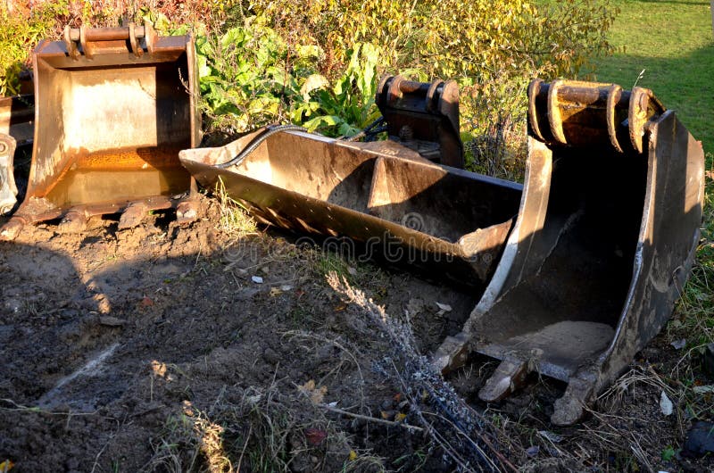 There are high piles of soil on the construction site during excavation work. unich lies on the lawn aside, bucket excavator. Excavators and bulldozers are different types of tools. There are high piles of soil on the construction site during excavation work. unich lies on the lawn aside, bucket excavator. Excavators and bulldozers are different types of tools