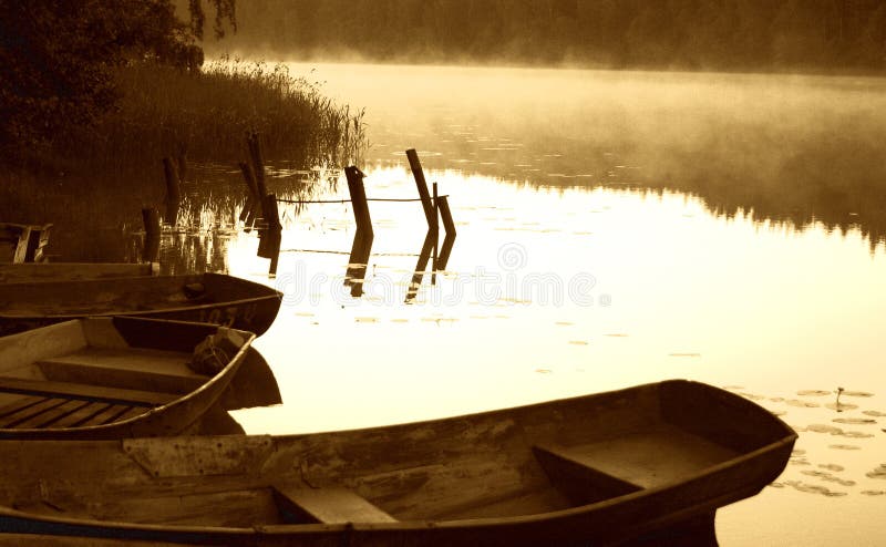 Esboço do amanhecer pelo lago nevoento com barcos imagem de stock Esboço do amanhecer pelo lago nevoento com barcos imagem de stock