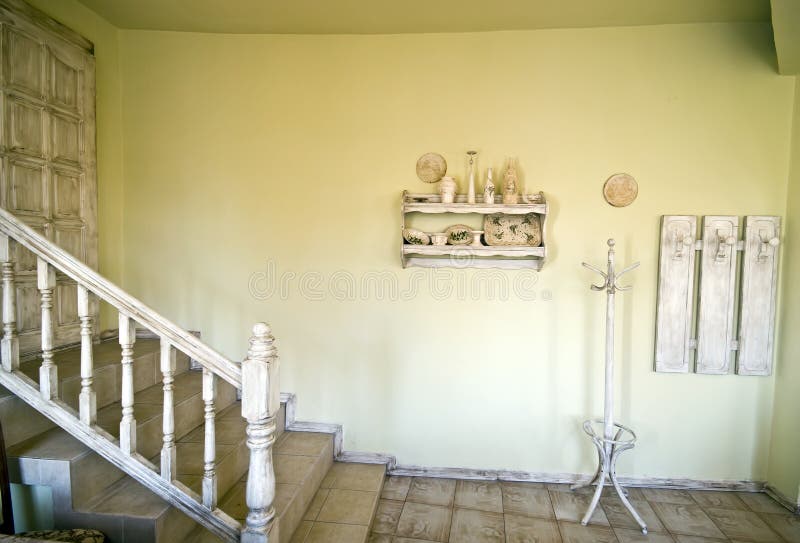 A rustic house interior with stairs leading to a door, clothes hangers at the right. A rustic house interior with stairs leading to a door, clothes hangers at the right.