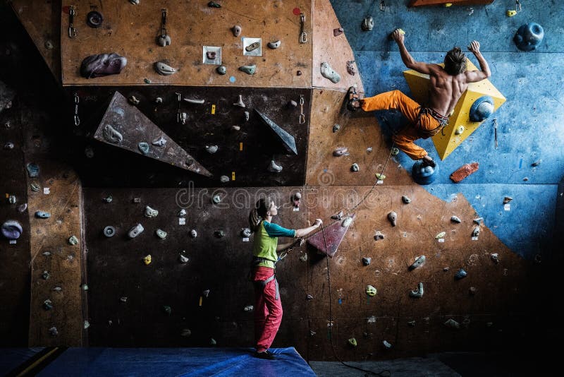 Muscular men practicing rock-climbing on a rock wall indoors. Muscular men practicing rock-climbing on a rock wall indoors