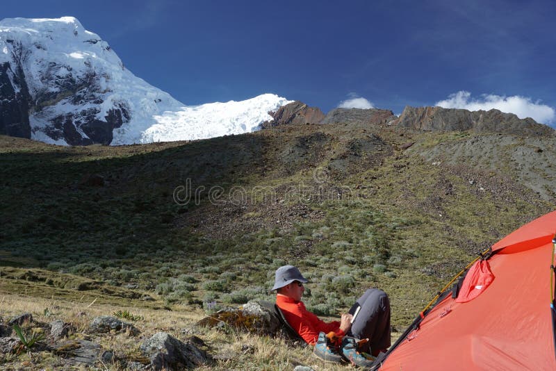 Escalador de montaña que se sienta fuera de una tienda y que escribe en su diario en el Blanca de Cordillera en Perú fotografía de archivo libre de regalías Escalador de montaña que se sienta fuera de una tienda y que escribe en su diario en el Blanca de Cordillera en Perú fotografía de archivo libre de regalías