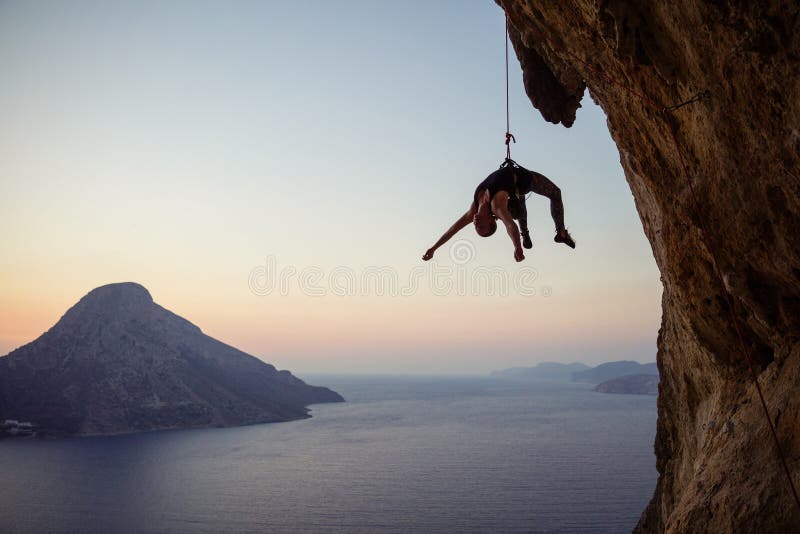 Escalador de roca femenino joven que cuelga en cuerda mientras que siendo bajado