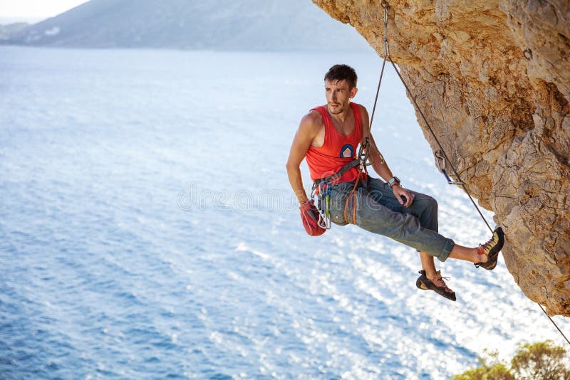 Escalador de roca masculino que descansa mientras que cuelga en cuerda