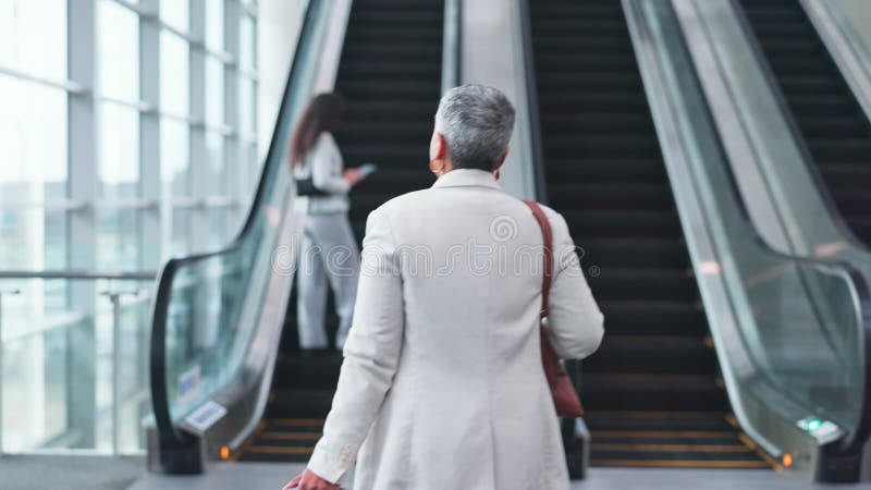 Escaladora de aeroporto e empresária com bagagem para viagens em trânsito e chegada ao lobby. construção moderna