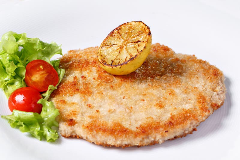 Escalope de veau allemande avec des citrons et des chaux, des tomates et salade de laitue du ` s d'agneau photographie stock Escalope de veau allemande avec des citrons et des chaux, des tomates et salade de laitue du ` s d'agneau photographie stock
