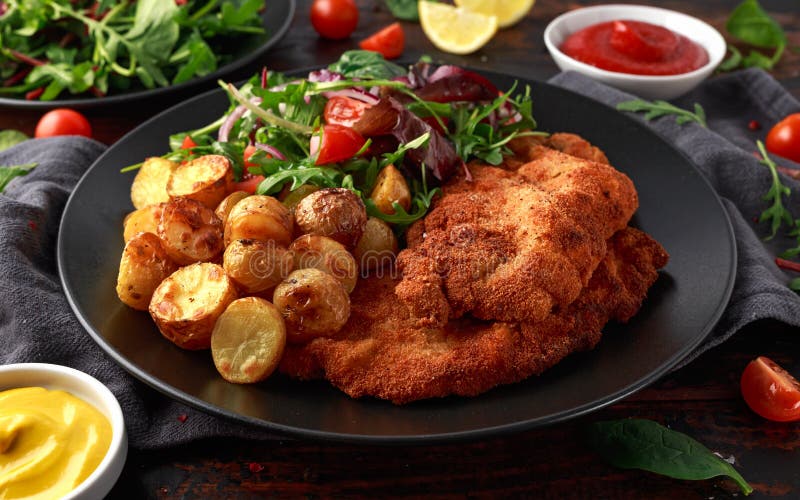 Escalope de veau panée faite maison de porc avec la pomme de terre et les légumes de rôti photos libres de droits Escalope de veau panée faite maison de porc avec la pomme de terre et les légumes de rôti photos libres de droits