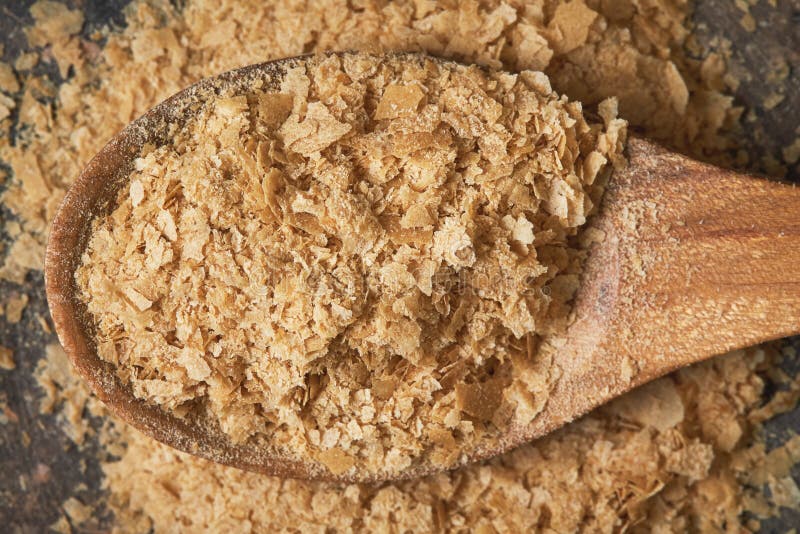 Nutritional brewers yeast flakes in wooden spoon. Top view. Nutritional brewers yeast flakes in wooden spoon. Top view